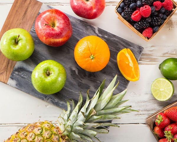 berries, citrus and apples on a cutting board