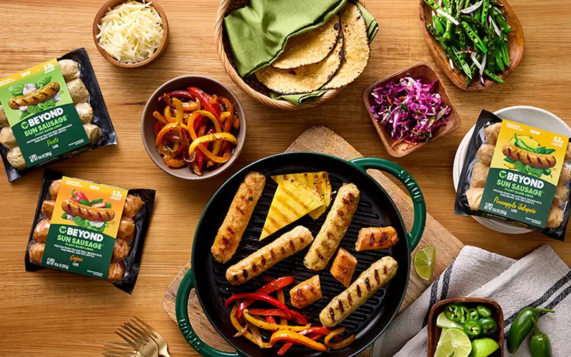 Beyond sausage varieties next to a pan of cooked sausage